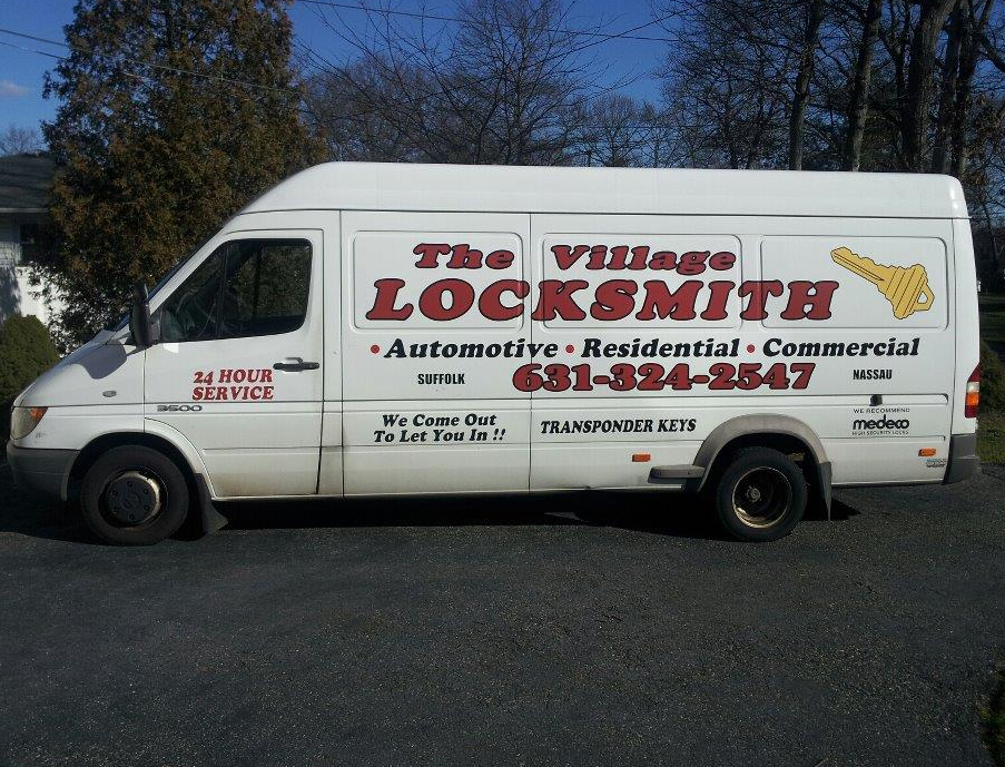 A white commercial van for The Village Locksmith, advertising 24-hour service for Automotive, Residential, and Commercial locksmith work, including floor safe installation, serving Suffolk and Nassau. The company phone number is 631-324-2547.